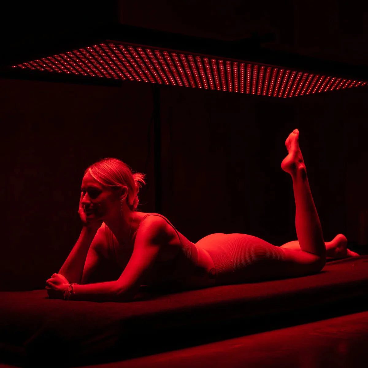 woman laying under full body infrared light therapy.